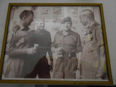 Copy of four servicemen engaged in a conversation enjoying a beer.