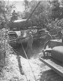 A black and white photograph of Diggers from 1st Armoured Regt strain to pull a thrown track off a Centurion Tank