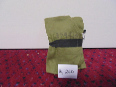 Green fabric sewing kit, with three small pouches secured by a black belt. 