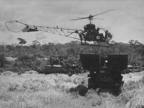 A black and white photograph of a helicopter of 161 (Indep) Recce Flt uses a Centurian Tank Bridge Layer as a landing zone during Operation Matilda