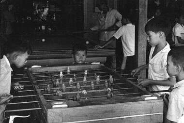 A black and white photograph of Vietnamese children playing a game of soccer in a Penny Arcade in the heart of the provincial capital Baria