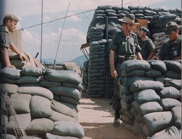 A coloured photograph of three members of AATTV and an American man the most forward northern base in South Vietnam