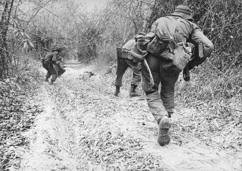 A photograph of TAOR patrol, Long Binh Operation Federal, 7 platoon, C Coy 4 RAR/NZ under heavy fire from both sides of the road. 