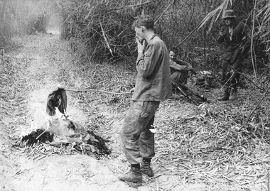 A photograph of, TAOR patrol, Operation Federal  7 Platoon, C Company  4 RAR/NZ , a digger burns uniforms and packs captured during the firefight.