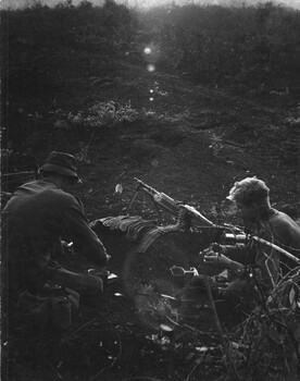 A photograph of two diggers with the 9th Battalion,  Royal Australian Regiment,  brew up a quick cup of coffee. 