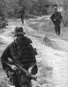 A photograph of diggers of 7 Platoon, C Company, 4 RAR/NZ (ANZAC) patrolling in the "light Green" around the giant Uunited States supply complex. 