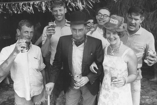 A photograph at 1st Australian Field Hospital, Medic in a bowler hat, accompanied by the Red Cross Rosemary Griggs welcome guests to a party. 