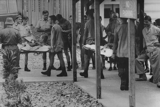 A photograph of staff and patients at the 1st Australian Field Hospita,l watch patients being medivaced loaded into ambulances. 