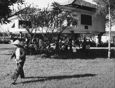 At the French owners house at a rubber plantation becomes a shady nook for the staff and workers as they await to be interrogated. 