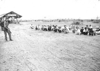 A photograph of a 5th Battalion, Royal Australian Regiment, digger guards Binh Ha villagers awaiting interrogation and identity checks. 