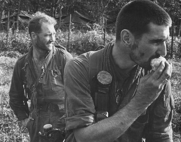 A tired and dirty Pte Jack Higgins about to enjoy a peeled orange while his boss Maj Jake O'Donnell. 7 RAR watches his company. 