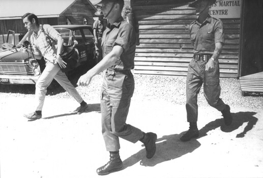 Pte Peter A. Allen of 9 RAR is escorted by a MP from the Court Marshall Centre at the 1st Logistic Support Base.  