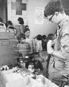 A medic from 161 Recce Flt gives vitamin pills to children during at Xuyen Moc after the township had been cleared of VietCong. 