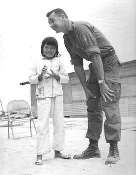 Australian Army Training Team Vietnam advisor Keith "Windy" Windbank talks to Hanh, who had lost her right eye and part of her nose. 