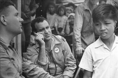 RAAF Medical Officer and a RAAF Medic assess a young Vietnamese boy born with his ears deformed, during a Medcap at Bong Son Island. 