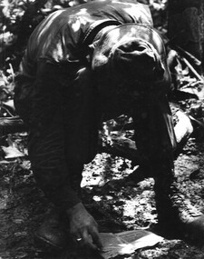 A photograph of a digger 'Vietnamese Linguist' attached to 1st Australian Task Force, NVA/VietCong documents captured during a battle in the Hat Dich area. 