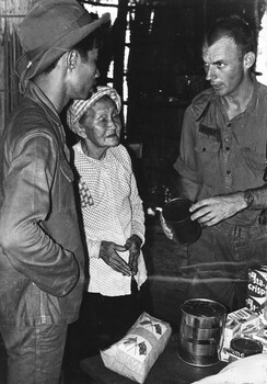 2Lt Mike Meehan of 161 (Indep) Recce Flight, explains to a local female villager the type and use of the food packages. 