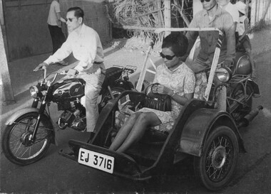 A black and white photograph of a Vietnamese 'cyclo taxi' as weaves its way through the traffic in Saigon.  