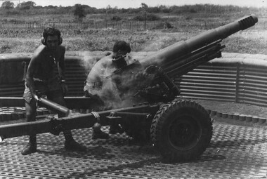 A digger throws away a spent shell casing from a 105mm Italian Pack Howitzer during a fire mission from the 1st ATF Base.