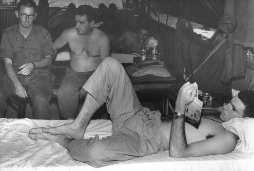 Soldiers sitting in 2 Field Ambulance Hospital ward, the C.O. Capt Jack (The Quack) Blomley, discusses the problems of the Dental Department.