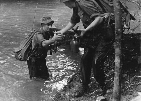 Jack Higgins gets a helping hand from Maj O'Donnell with a heavy pack on his back gets a helping hand up a slippery bank. 