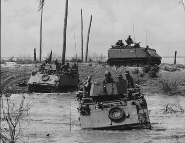 An Armoured Personnel Carriers from the 1st Australian Task Force Base ferry infantry elements across a swollen river.