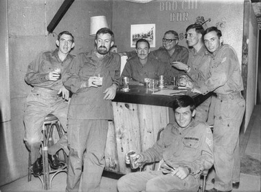 A black and white photograph of seven Diggers enjoy refreshemnts at the Bao Chi Bar 