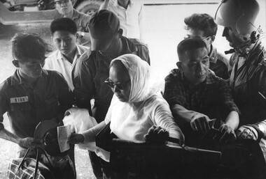 A VIP Vietnamese Colonel, his family and his Aide-de-Camp gets a helping hand from Crew Chief Cpl Allan Hudson as "first country nationals".