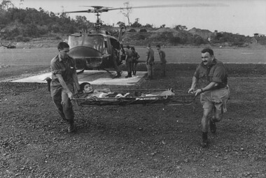 Medics from the 8th Field Ambulance Hospital unload a second Americam dustoff medical evacuation helicopter bringing wounded NVA/Viet Cong. 