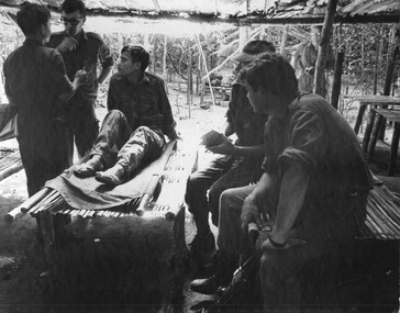 A South Vietnamese Intelligence Officer translates for the 6 RAR/NZ Intelligence Officer as a patient captured in his bed. 