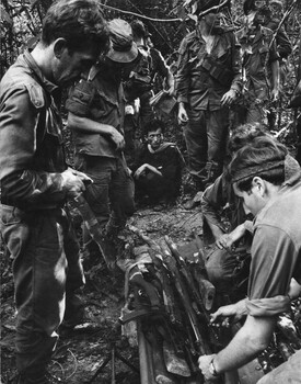 The CO of 6 RAR/NZ Lt Col Butler, his Radio Operator and Intellegence Officer inspects the weapons found in the large underground cache. 