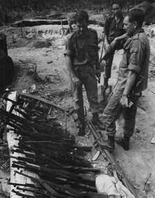 The CO of 6 RAR/NZ Lt Col Butler, his Radio Operator and Intellegence Officer inspect weapons found in the cache at the K76A Hospital. 