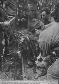 A Digger straps captured NVA/VietCong weapons to a stretcher, found in a cache disclosed by the enemy VietCong prisoner at the VietCong, at the K76A Hospital. This led the Aussies t man such caches.