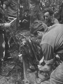 A Digger straps captured NVA/VietCong weapons to a stretcher found in a cache disclosed by the enemy VietCong prisoner. 