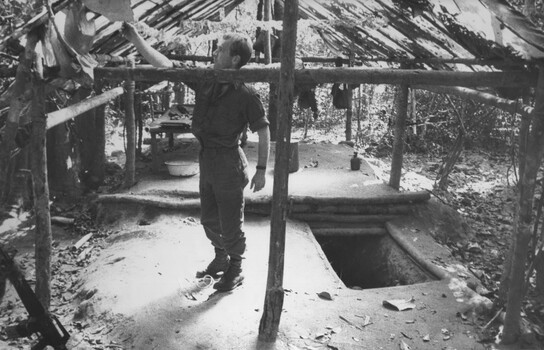 A photograph of a Digger checking out the Doctor's Quarters near one of the wards at the NVA/VietCong K76A Hospital captured during Operation Marsden.
