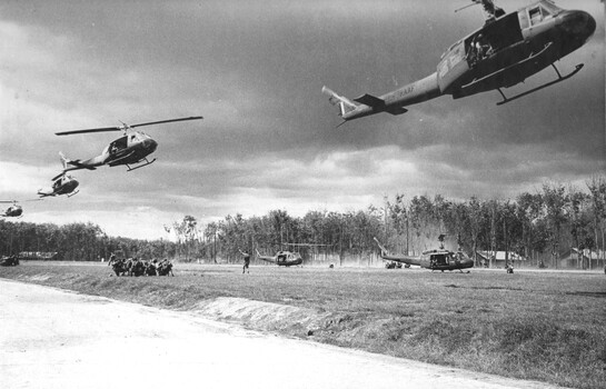 A photograph of RAAF No: 9 Squadron, Huey "Slick" Helicopters, pickup Diggers at Kanga Pad, 1st Australian Task Force Base Nui Dat. 