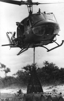 A RAAF Huey delivers 44 gallon drums of diesel to an Australian Fire Support Base for refuelling APC's and Centurian tanks supporting infantry operations.