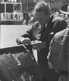 A photograph in Townsville, 18/08/1968. The Prime Minister of Australia, John Gorton fixes the "Long Tan Streamer" to the colours of 6th Battalion, The RAR.