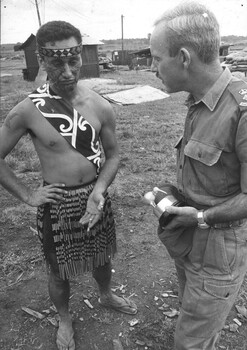 A photograph of Lt Col Morrison, C.O. , 9th Battalion. The  RAR,  discusses the "Maori Challenge"  which  been completed by a New Zealand Maori gunner.