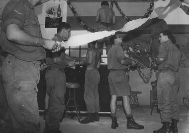 A photograph of Diggers at 1st Australian Task Force Base Headquarters hang Christmas decorations in their recreation hut. 