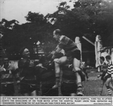 A photograph of Lt Col Naughton OBE CO 1st Field Hospital, is lifted onto the shoulders of his team mates during a rugby union game.