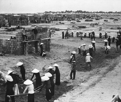 A photograph of Vietnamese refugees from the war in North Vietnam, mainly women, construct a refugee village at Tuy Hoa. 