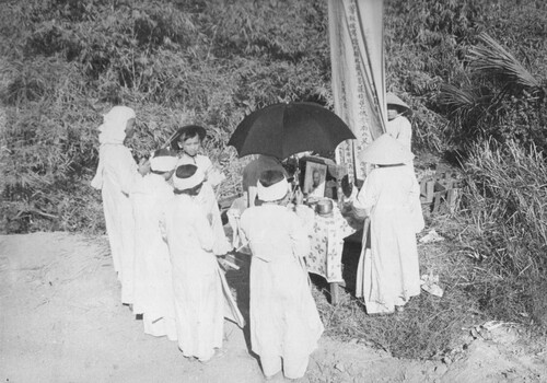 A photograph of an extended Vietnamese family worship at a shrine outside Hue, South Vietnam. 