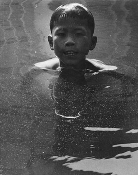 A photograph of a Vietnamese 'street wise boy' has his early morning wash in a fountain in central Saigon. 