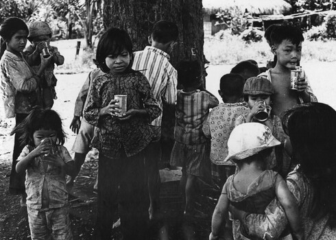 A photograph of the village Children of Xuyen Moc enjoy chilled cans of chocolate and strawberry milk, given to them by 161 (Indep) Recce Flt.