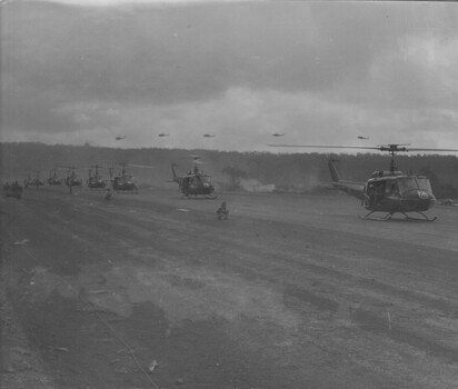 A photograph of an American assault Huey "slick" Helicopters, land at Eagle Farm helipad to collect Infantry Diggers from 1st Australian Task Force Base. 