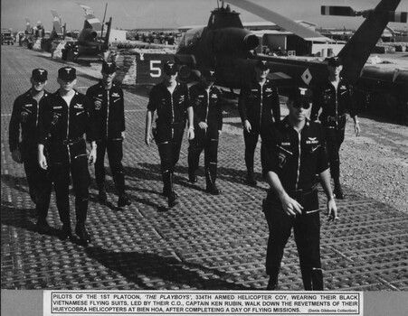 A photograph of Pilots of the 1st Platoon 'The Playboys' 334th Armed Helicopter Coy wearing their black Vietnamese flying suits. 