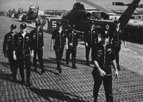 A photograph of Pilots of the 1st Platoon 'The Playboys' 334th Armed Helicopter Coy wearing their black Vietnamese flying suits. 