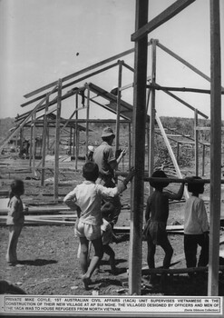 A photograph of Pte Mike Coyle, 1st Australian Civil Affairs Unit supervises Vietnamese in the construction of their new village at Ap Sui Nge. 