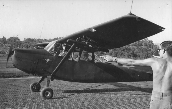 Capt Bernie Forest in his 161 (Indep) Recce Flt 'Possum' Cessna is directed to a parking bay by a member of the unit's ground staff.